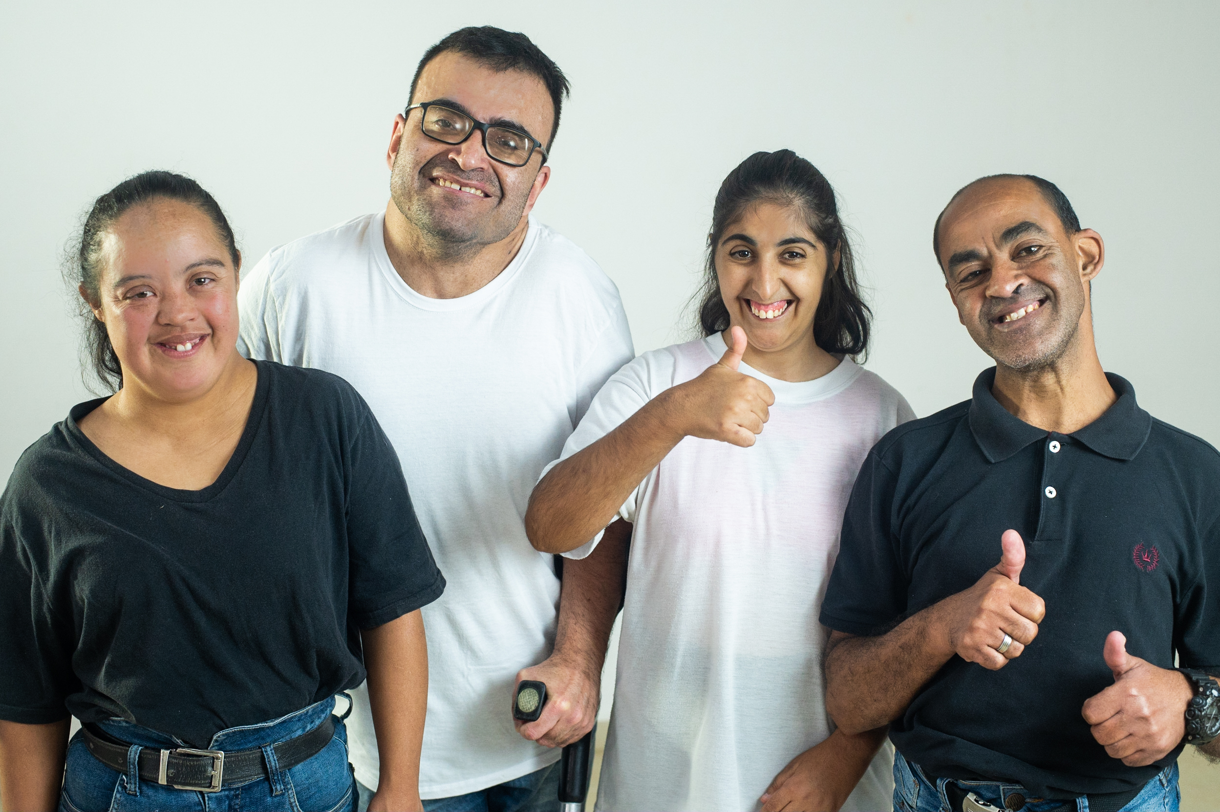 Grupo de quatro pessoas sorrindo e fazendo sinal de positivo